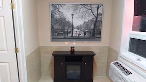 Habitación de esquina con chimenea, radiador y un cuadro en la pared.