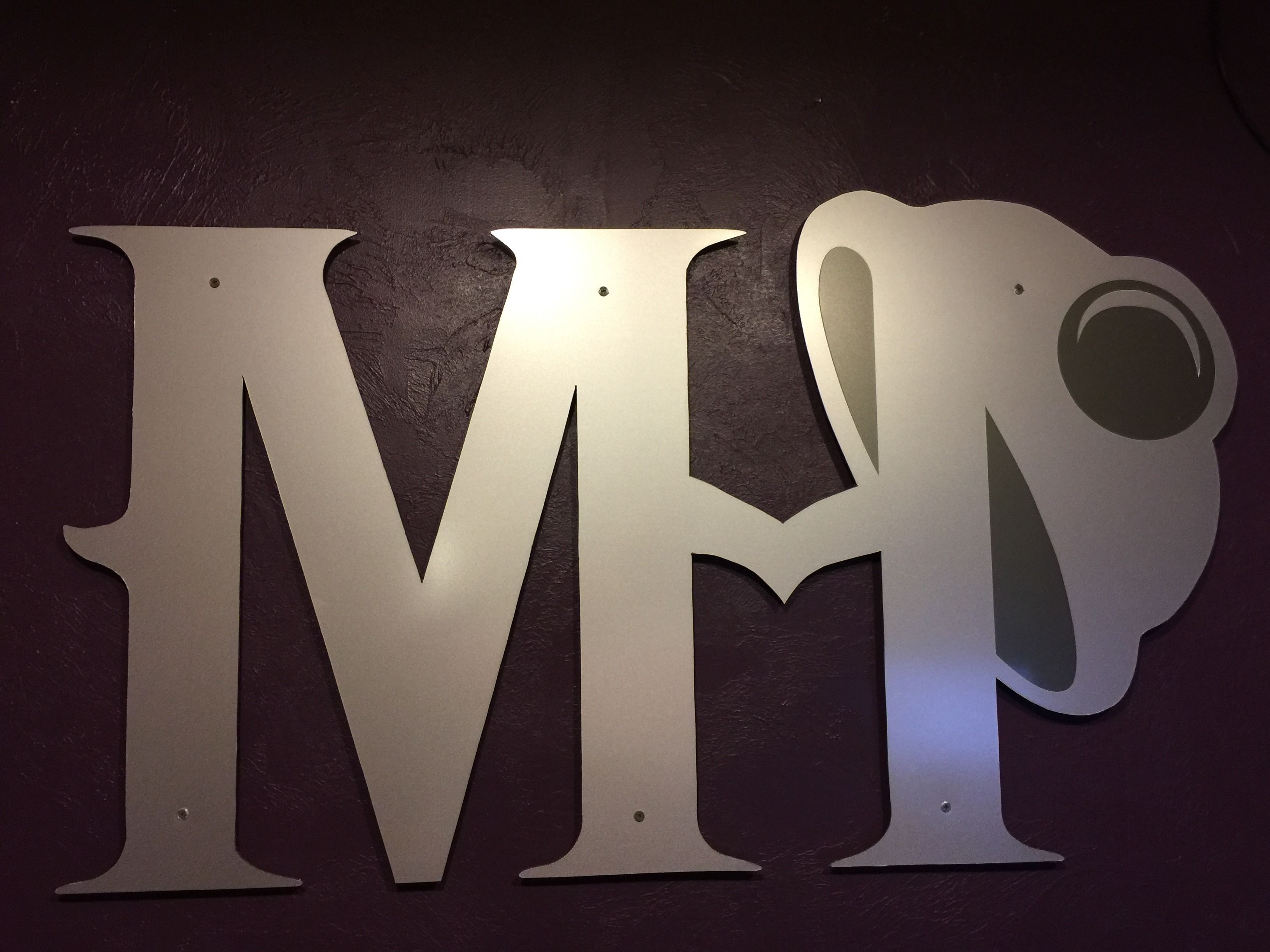 Una pared con letras metálicas grandes que deletrean "MI" y una letra "R" incompleta.