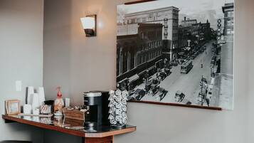 Una estación de café con una fotografía antigua de una escena callejera, una lámpara de pared y un cubo de basura.
