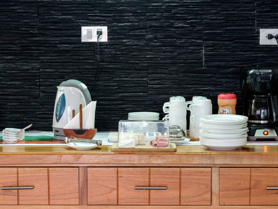 A kitchen counter with various appliances and items, including a kettle, coffee maker, and stacked plates.