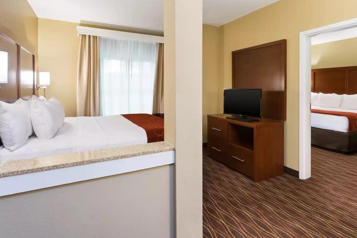 A hotel room with a bed, a TV, a desk, and a wardrobe.