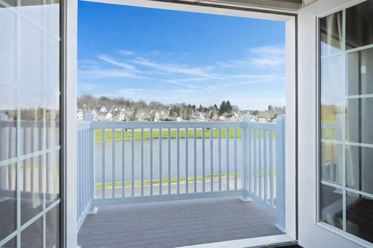 A balcony with a view of a lake and houses in the background.