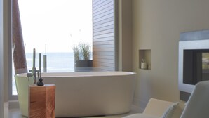Un salón moderno con un sofá blanco, una mesa de centro de cristal y vistas al mar a través de amplios ventanales.