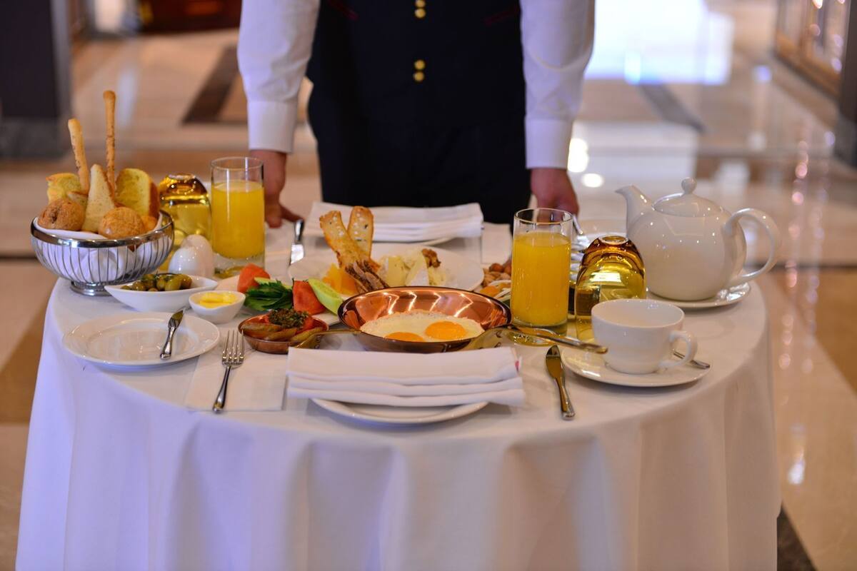 A breakfast buffet with various dishes, a pitcher of orange juice, and a teapot on a table.