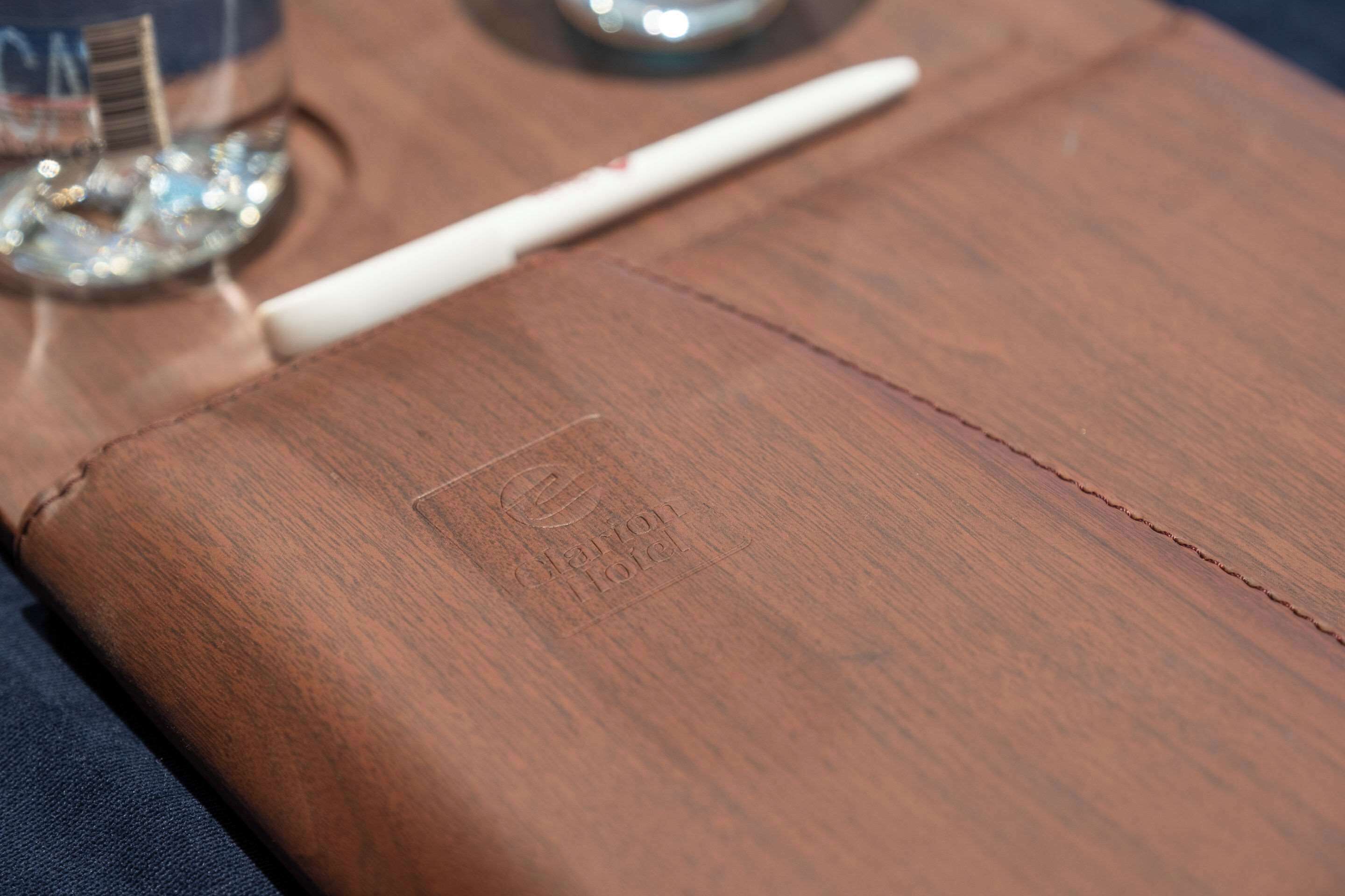 A close-up of a brown leather item with a visible stitching line and an embossed logo.