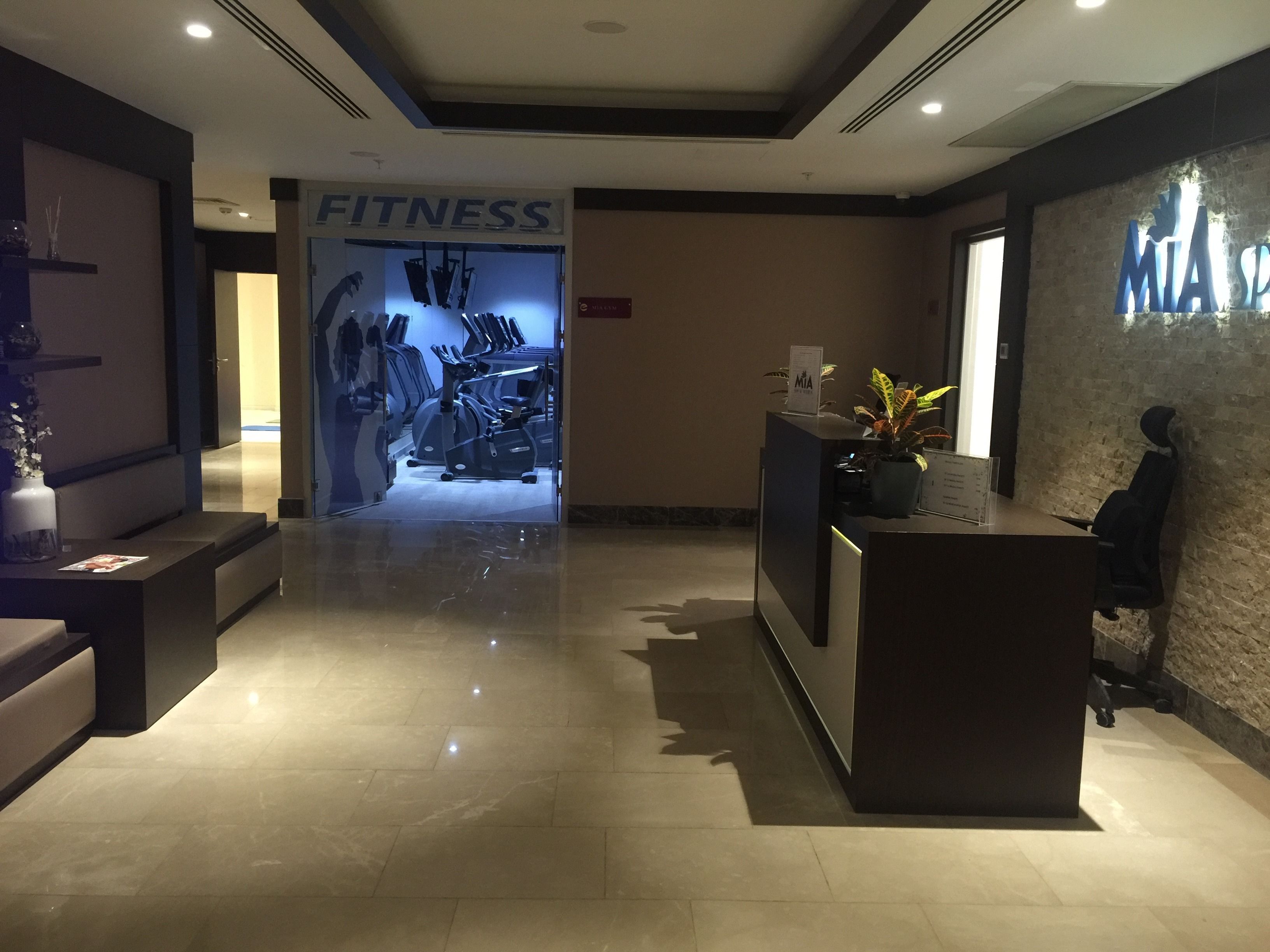 A fitness center with exercise equipment, a reception desk, and a reception area.
