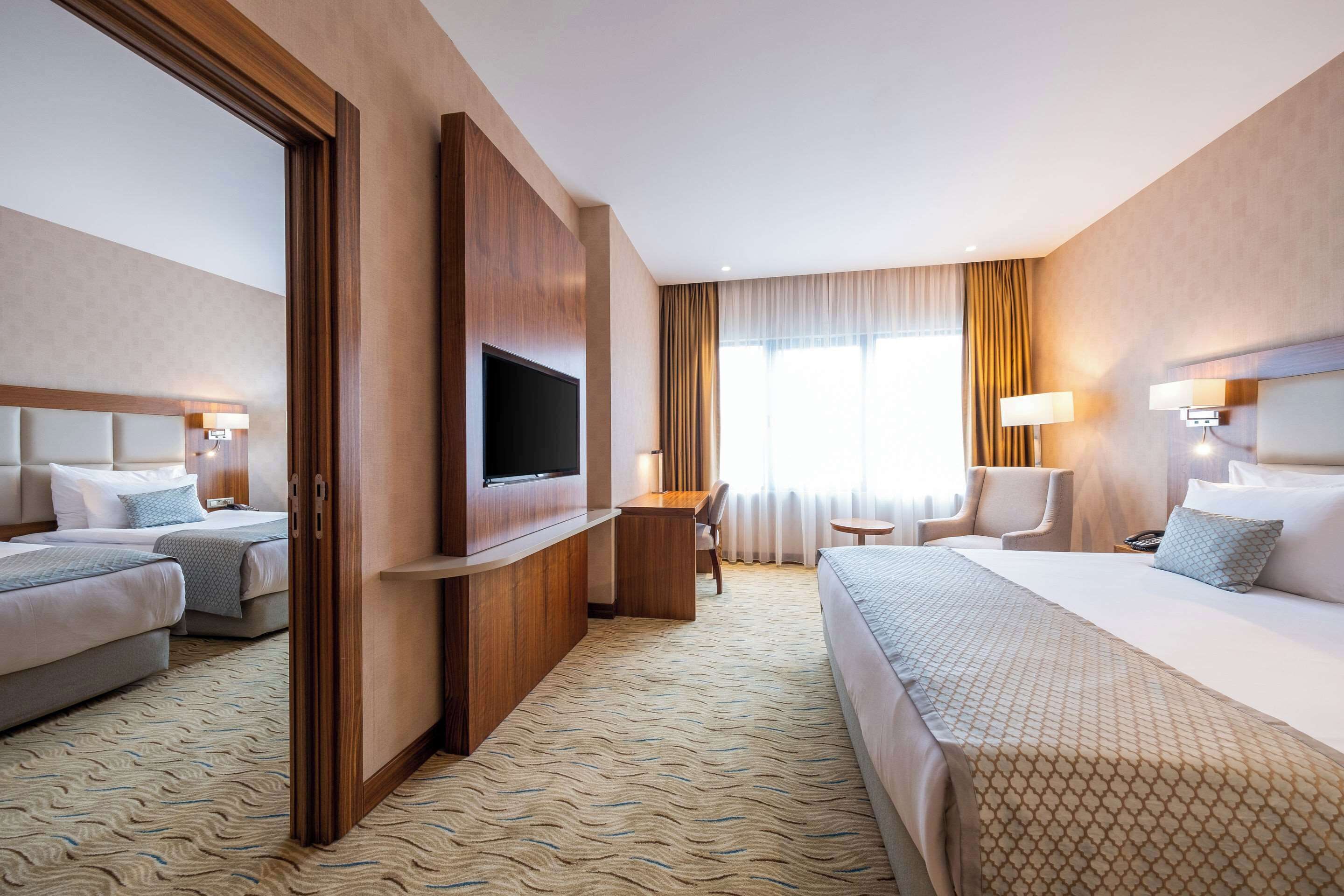 A hotel room with two beds, a TV, a desk, and a chair.