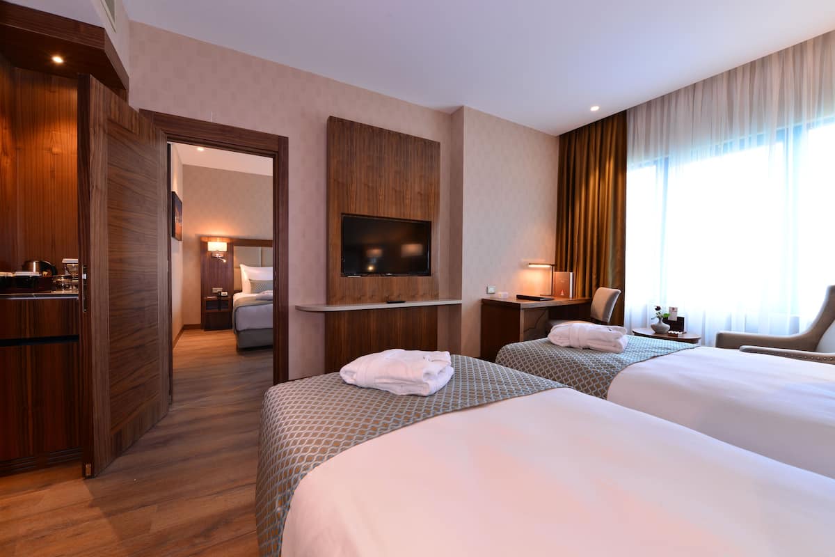 A hotel room with two beds, a TV, a desk, and a chair.