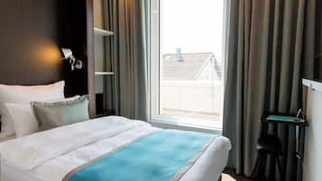 Ein Hotelzimmer mit Bett, Schreibtisch und einem fenster mit Vorhängen.
