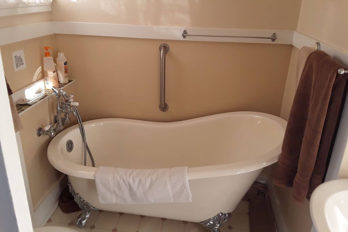 A bathroom with a freestanding bathtub, a toilet, a sink, and a towel rack.