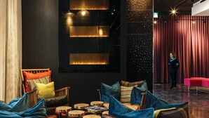 Un espace de détente moderne, avec des meubles en bois, des tables rondes et un rideau rouge en arrière-plan.