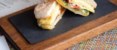 Un sandwich servi sur une planche en bois, avec une serviette noire placée en dessous.