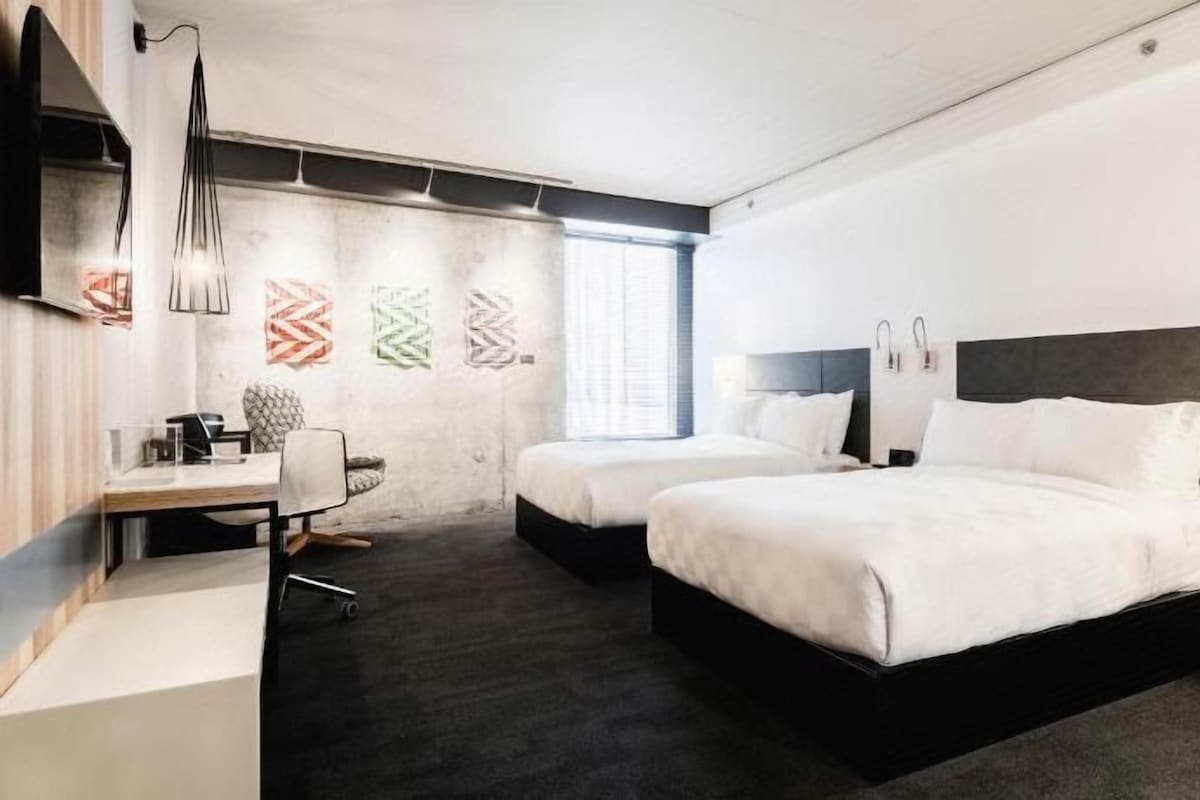 Una habitación de hotel con dos camas, un escritorio y una silla.