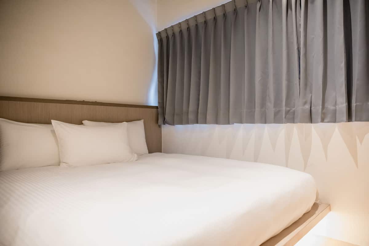 Una cama bien tendida con sábanas blancas y cabecera de madera.