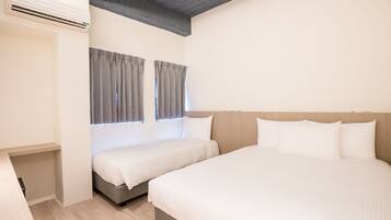 A hotel room with two beds, a wooden headboard, a built-in air conditioning unit, and a small bedside table.