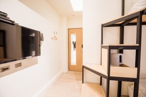 Una habitación de hotel moderna con un televisor de pantalla plana, camas literas de madera y una puerta que da a otra habitación.