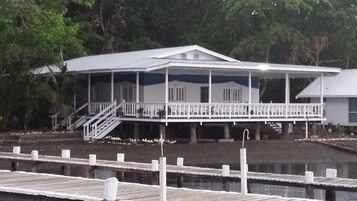 Una casa de dos pisos con un porche cubierto y un muelle que se adentra en el agua.