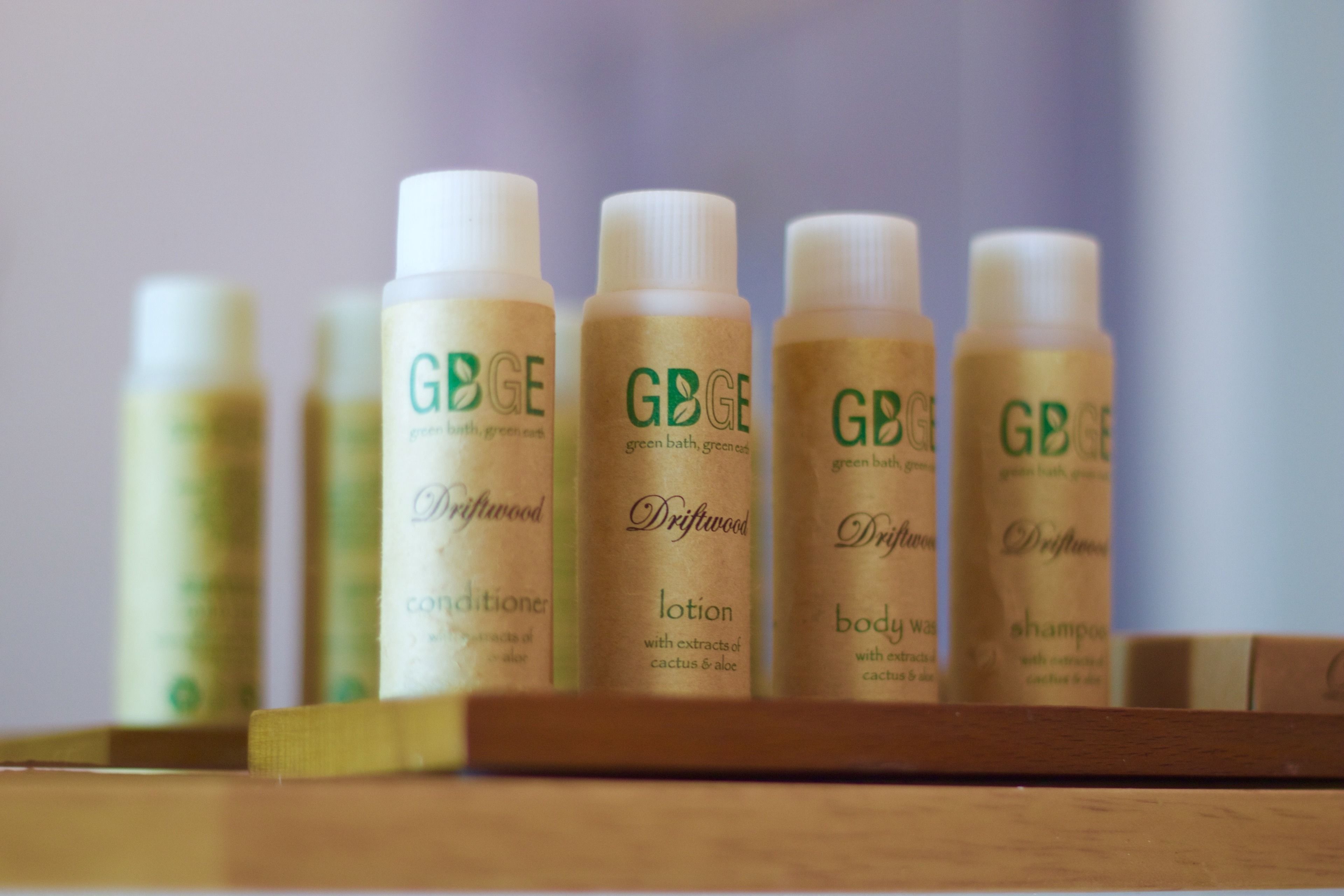Eine Reihe von Flaschen mit der Aufschrift 'GBGE' und verschiedenen Produktnamen wie 'Spülung', 'Lotion', 'Duschgel' und 'Shampoo'.