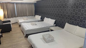 A hotel room with three beds, a desk, and a chair.