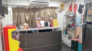 A reception area with a counter, air conditioning unit, and various items on display including a vending machine and a small refrigerator. - Sleep Taipei Hotel Nan-Ya Branch (New Taipei City)