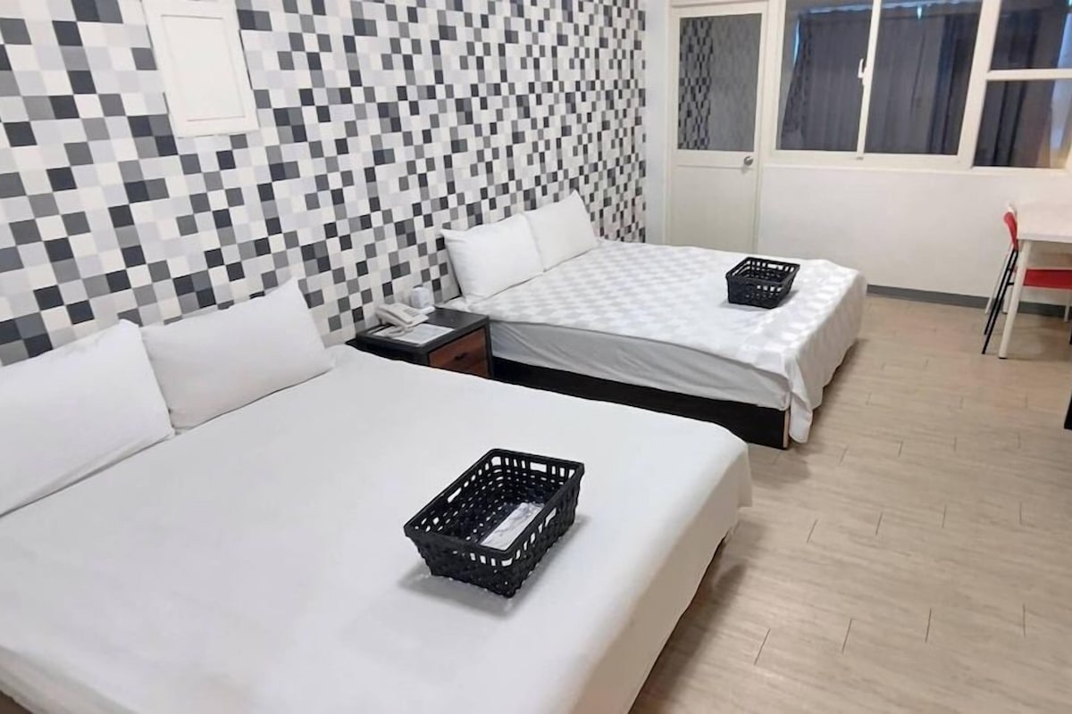 Una camera d'albergo con due letti, una scrivania, una sedia e una finestra.