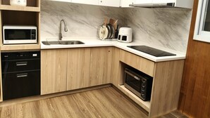 A modern kitchen with built-in appliances, a sink, and wooden cabinetry. - Success 66 B&B (Taitung)