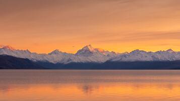 A mountain range reflected in a calm lake during sunset.