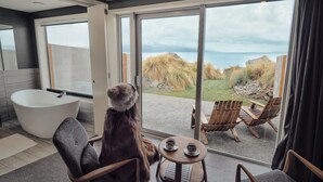 Un baño moderno con bañera, un espejo grande y vistas al exterior.