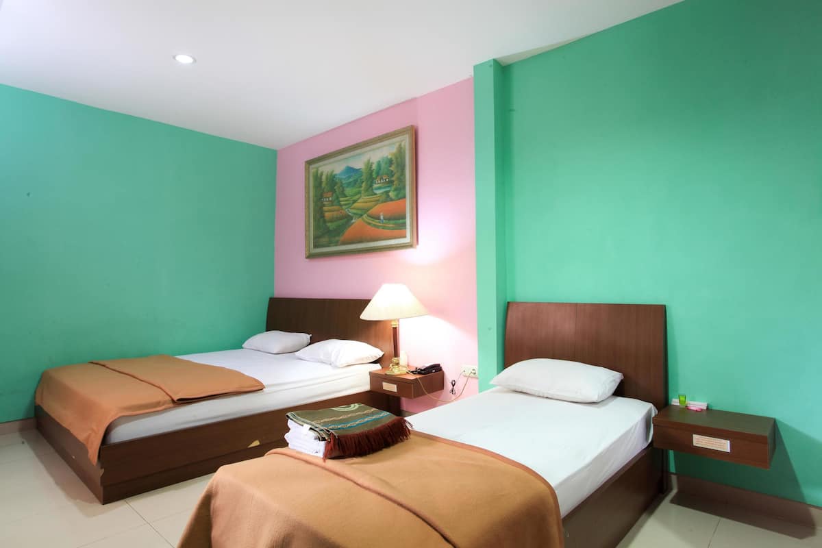 A hotel room with two beds, a nightstand with a lamp, a painting on the wall, and a green wall.