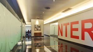 A modern corridor with a large 'INTER' sign on the wall, glass doors, and a polished floor. - Cabin Hotel (Jakarta)