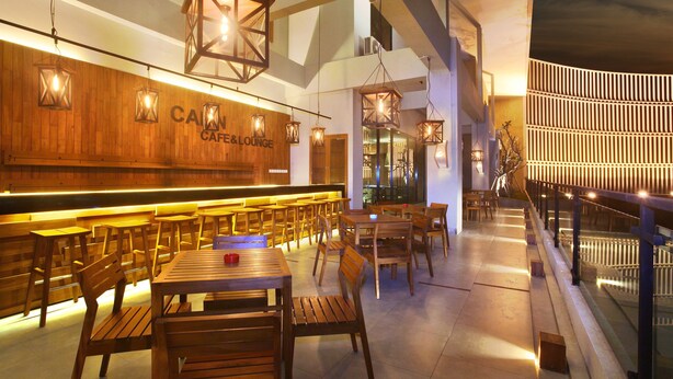 A spacious cafe with wooden furniture and hanging lanterns. - Cabin Hotel (Jakarta)