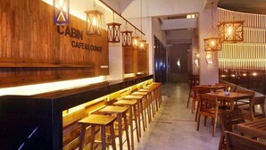 A modern interior with wooden accents, a bar area, and seating arrangements. - Cabin Hotel (Jakarta)