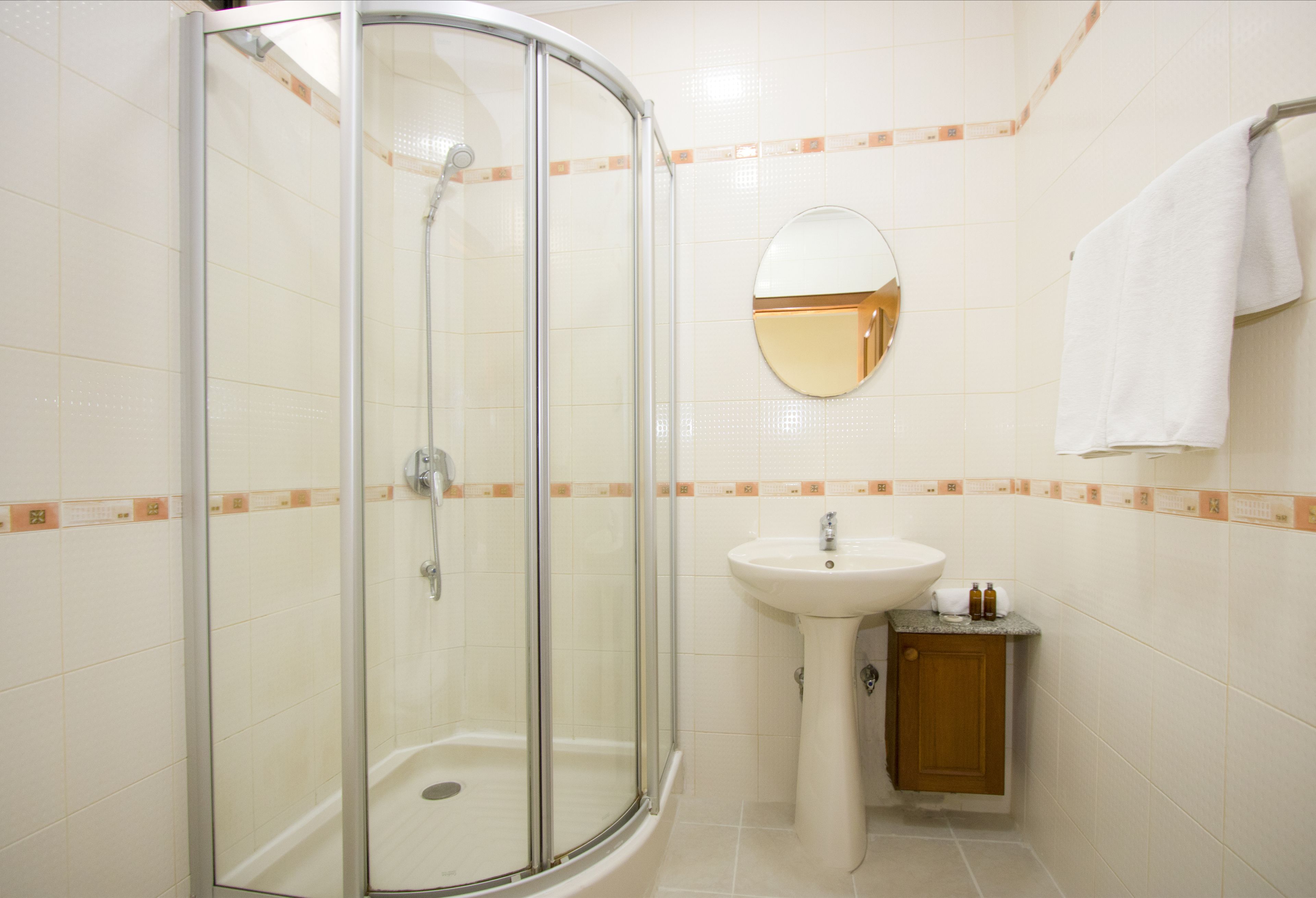 Ein Badezimmer mit einer Duschkabine aus Glas, einem Waschbecken und einem Spiegel.
