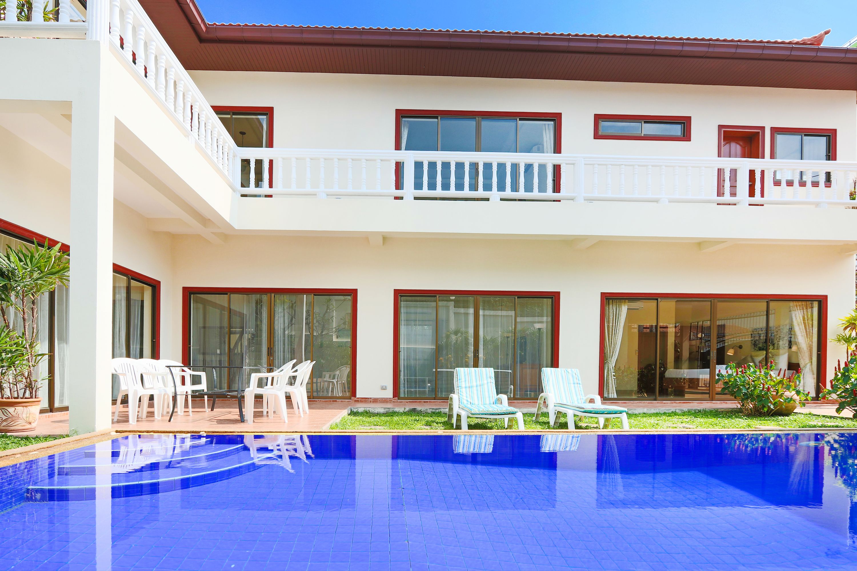 A two-story building with a swimming pool, outdoor seating, and a balcony.