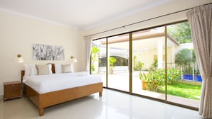 A bedroom with a large bed, a nightstand, a wall-mounted lamp, and a cityscape artwork. - Avoca Pool Villas (Pattaya)