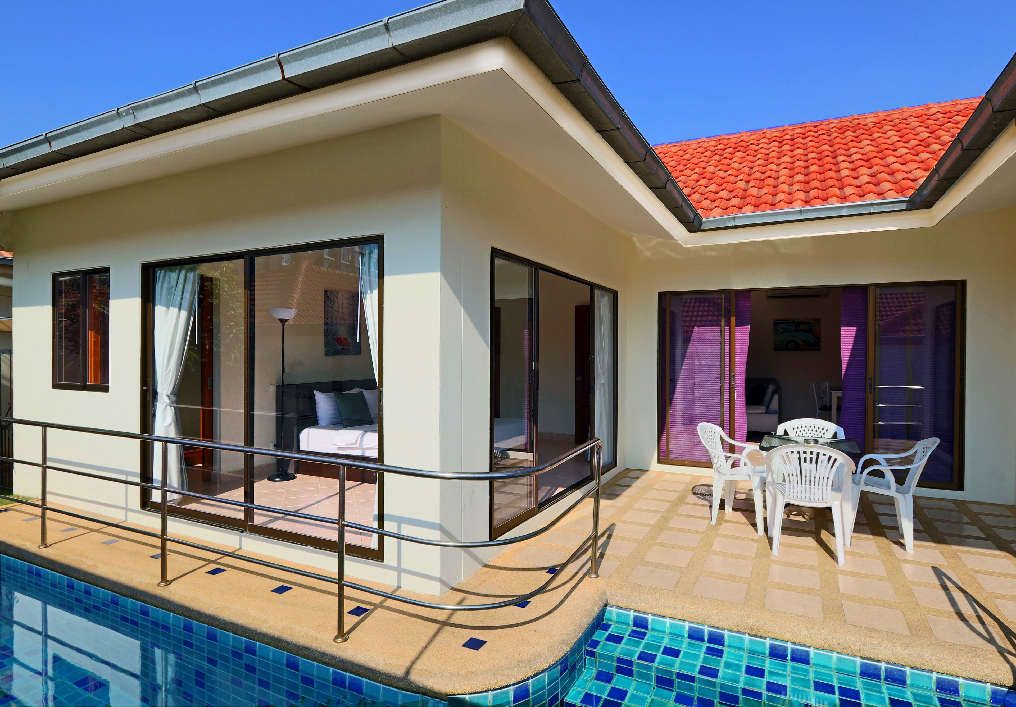 A modern hotel with a swimming pool, large windows, and a red-tiled roof.