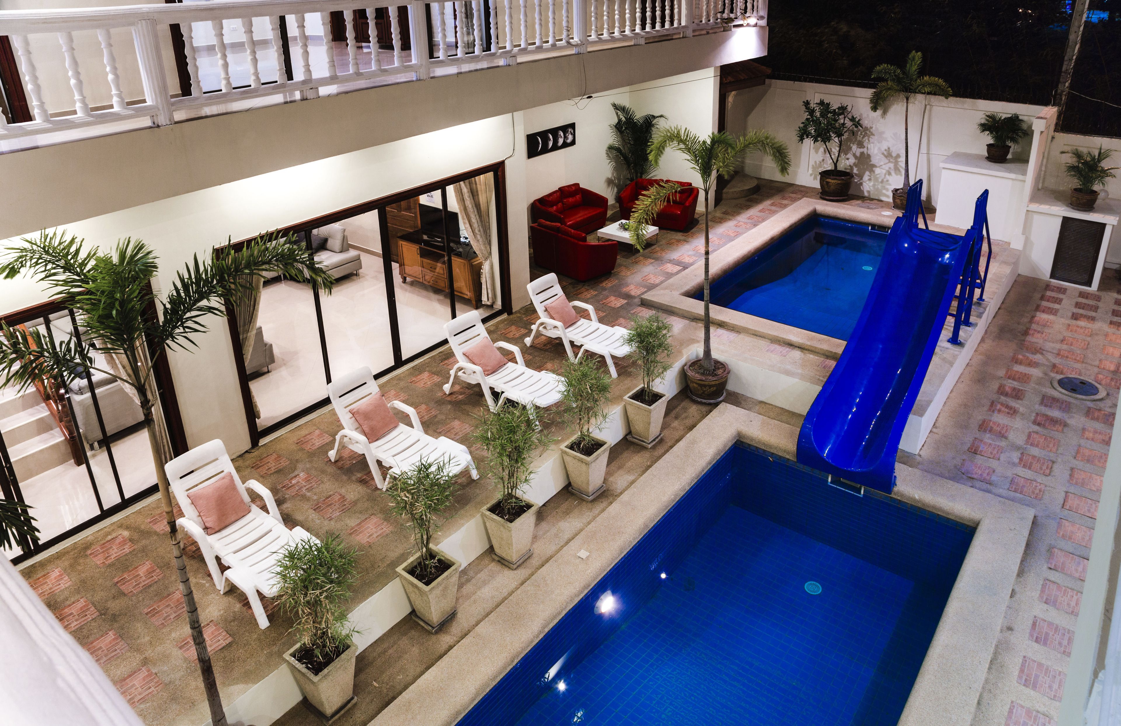 An outdoor pool area with lounge chairs, a slide, and potted plants.