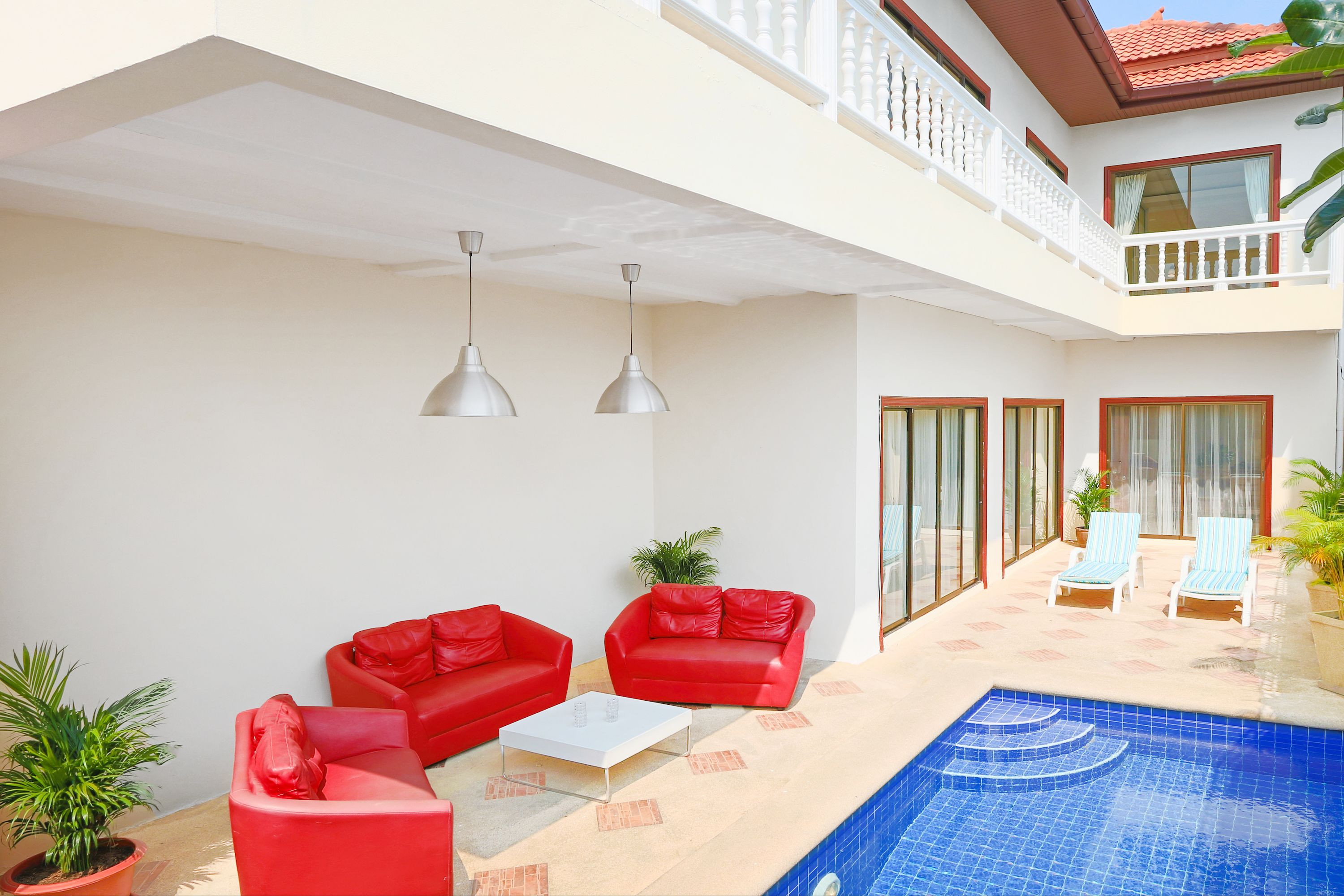 A spacious indoor area with a pool, red sofas, and two lounge chairs.