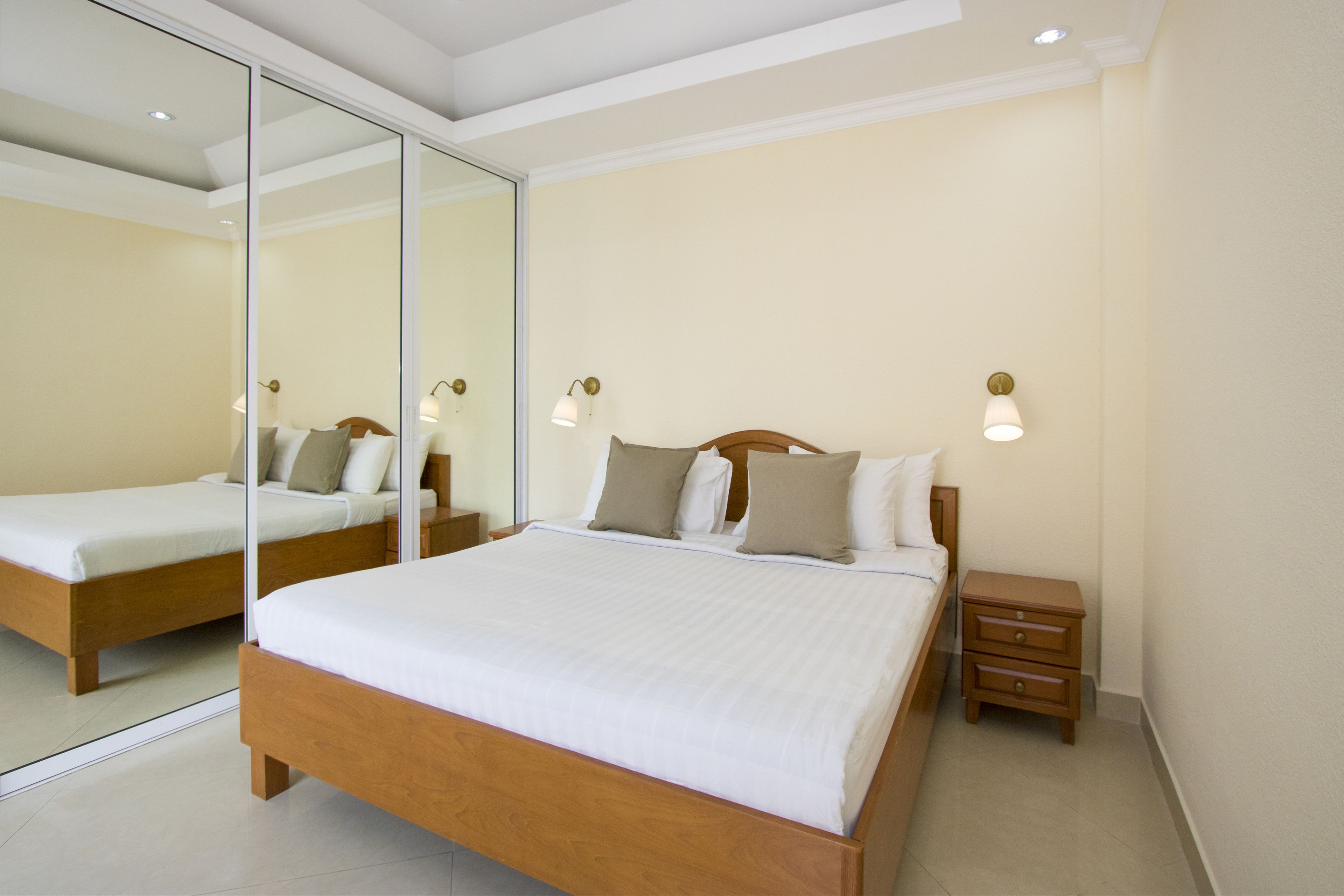 Une chambre à coucher moderne avec un grand lit, des tables de chevet et un miroir.