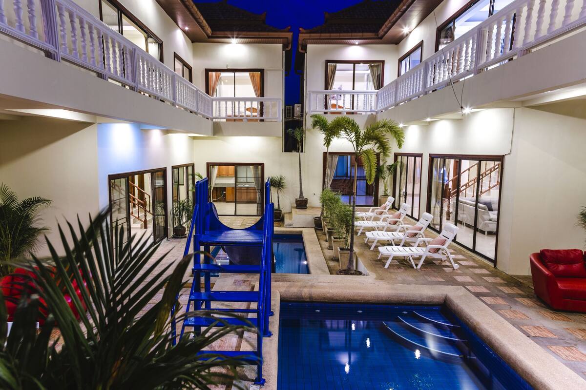A hotel interior with a pool, lounge chairs, and a blue chairlift.