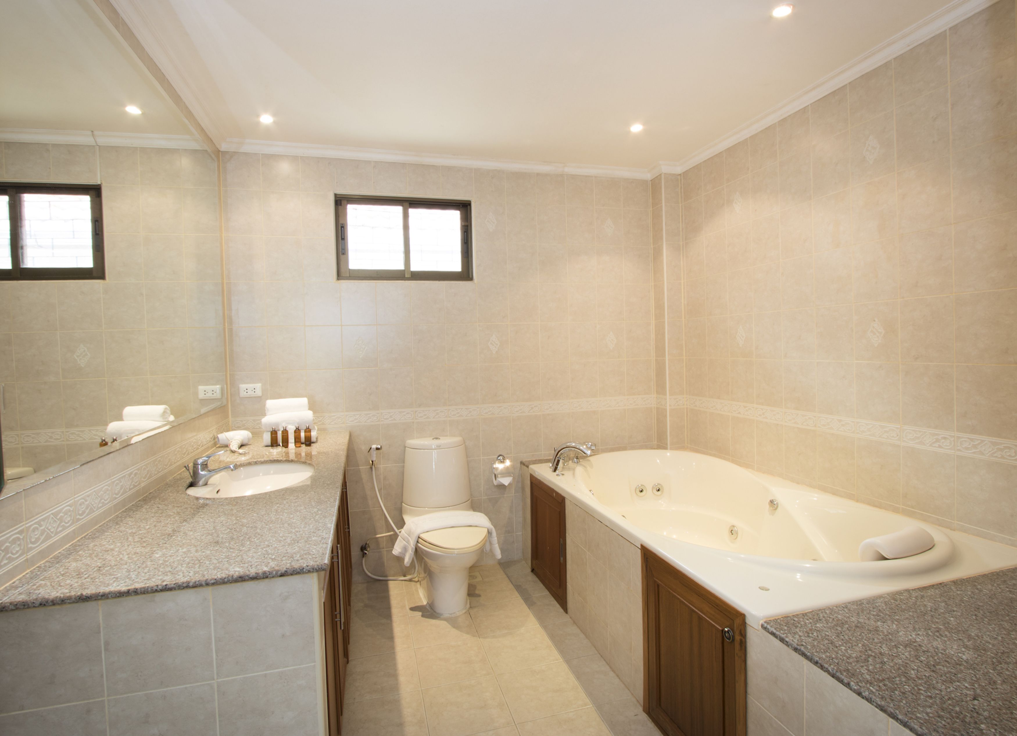 A spacious bathroom with a large bathtub, a separate shower area, and a vanity with a sink and mirror.