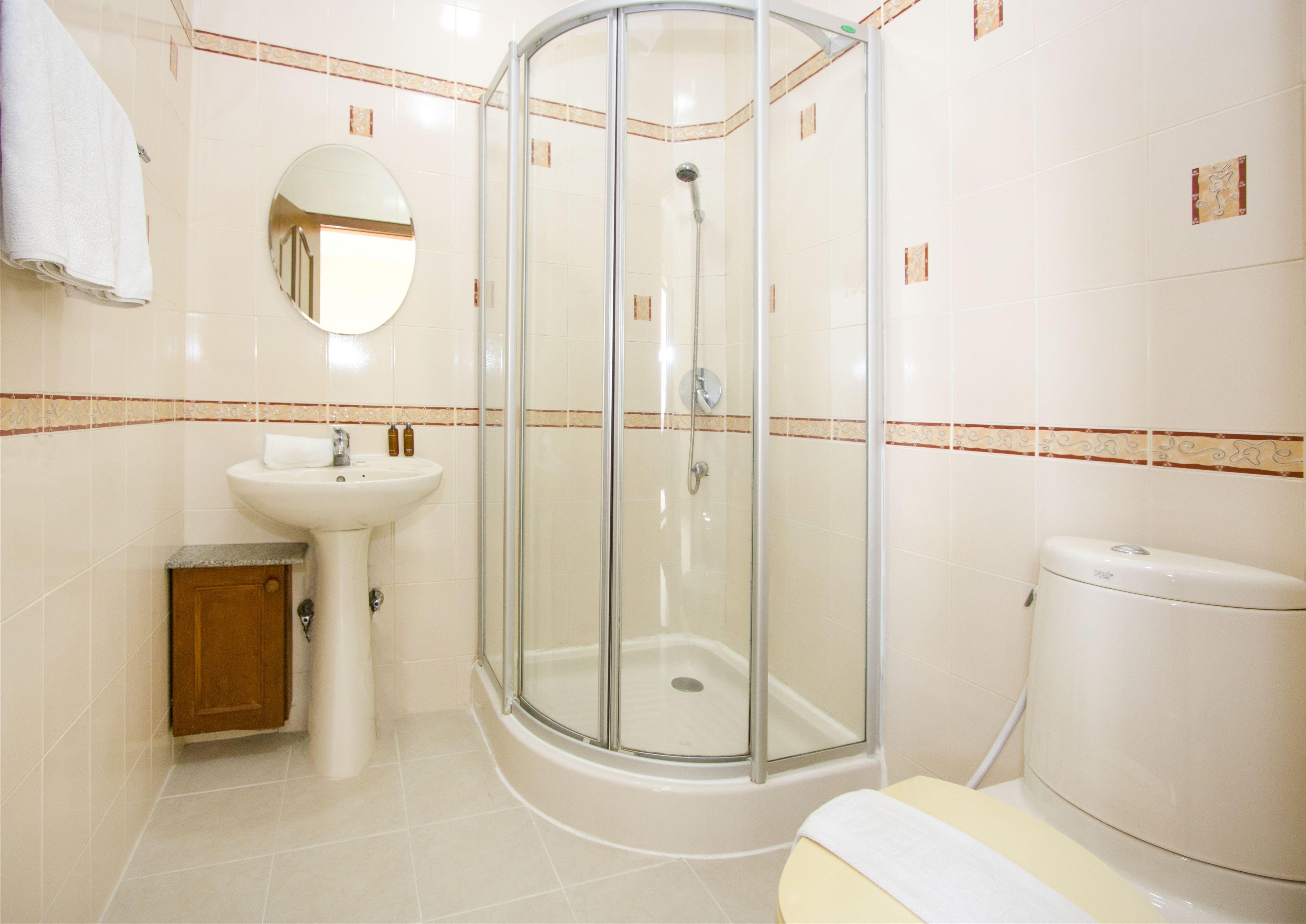 A bathroom with a glass-enclosed shower, a sink, a toilet, and a wooden cabinet.