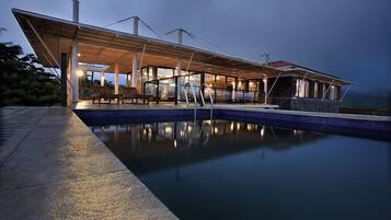 Ein moderner Poolbereich im Freien mit überdachter Lounge und Meerblick.
