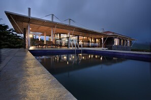 Ein moderner Poolbereich im Freien mit überdachter Lounge und Meerblick.