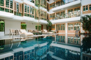 A modern hotel with a central pool, multiple balconies, and outdoor seating areas. - Moon Dragon Hotel (Chiang Mai)