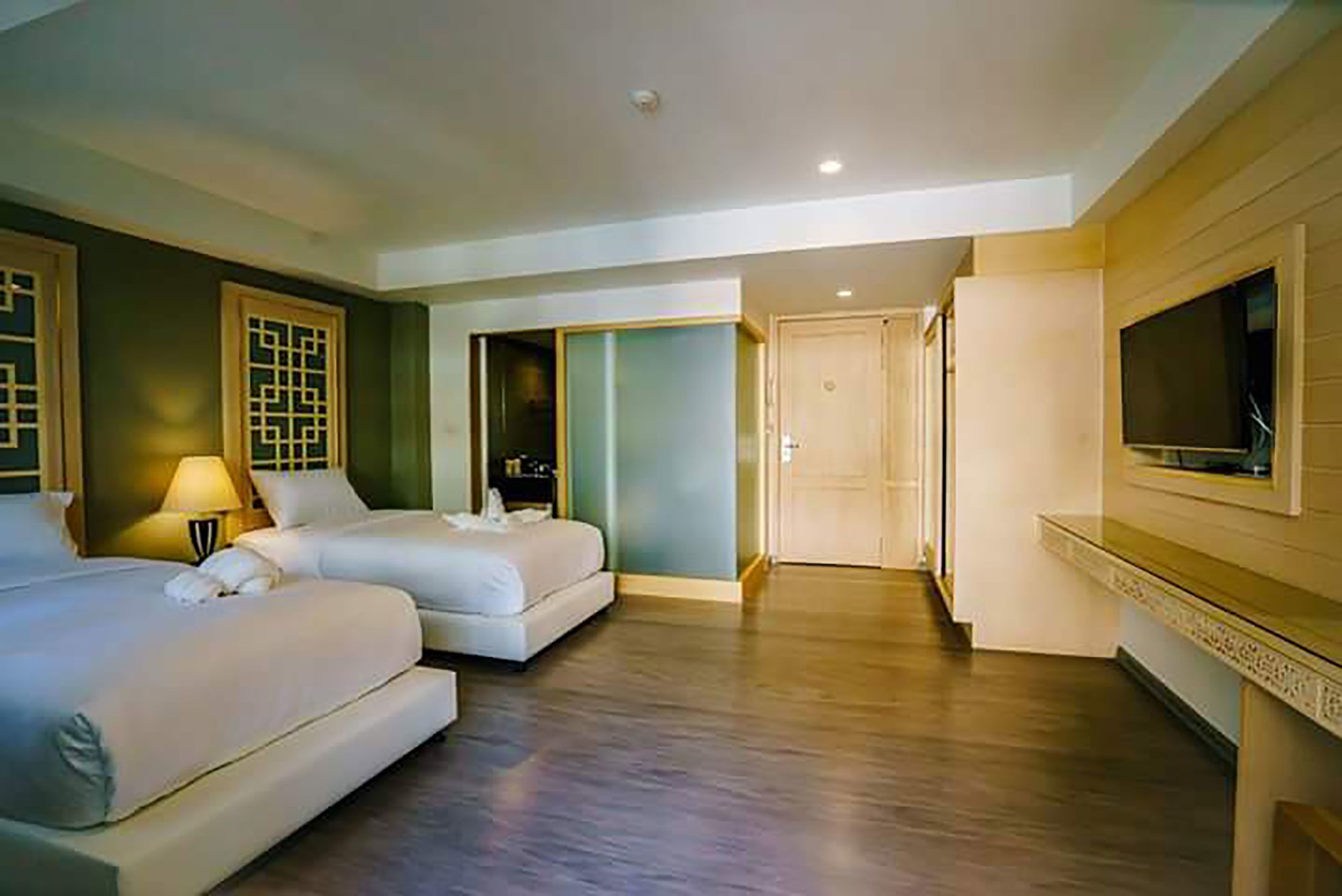 Habitación de hotel con dos camas, televisor, escritorio y armario.