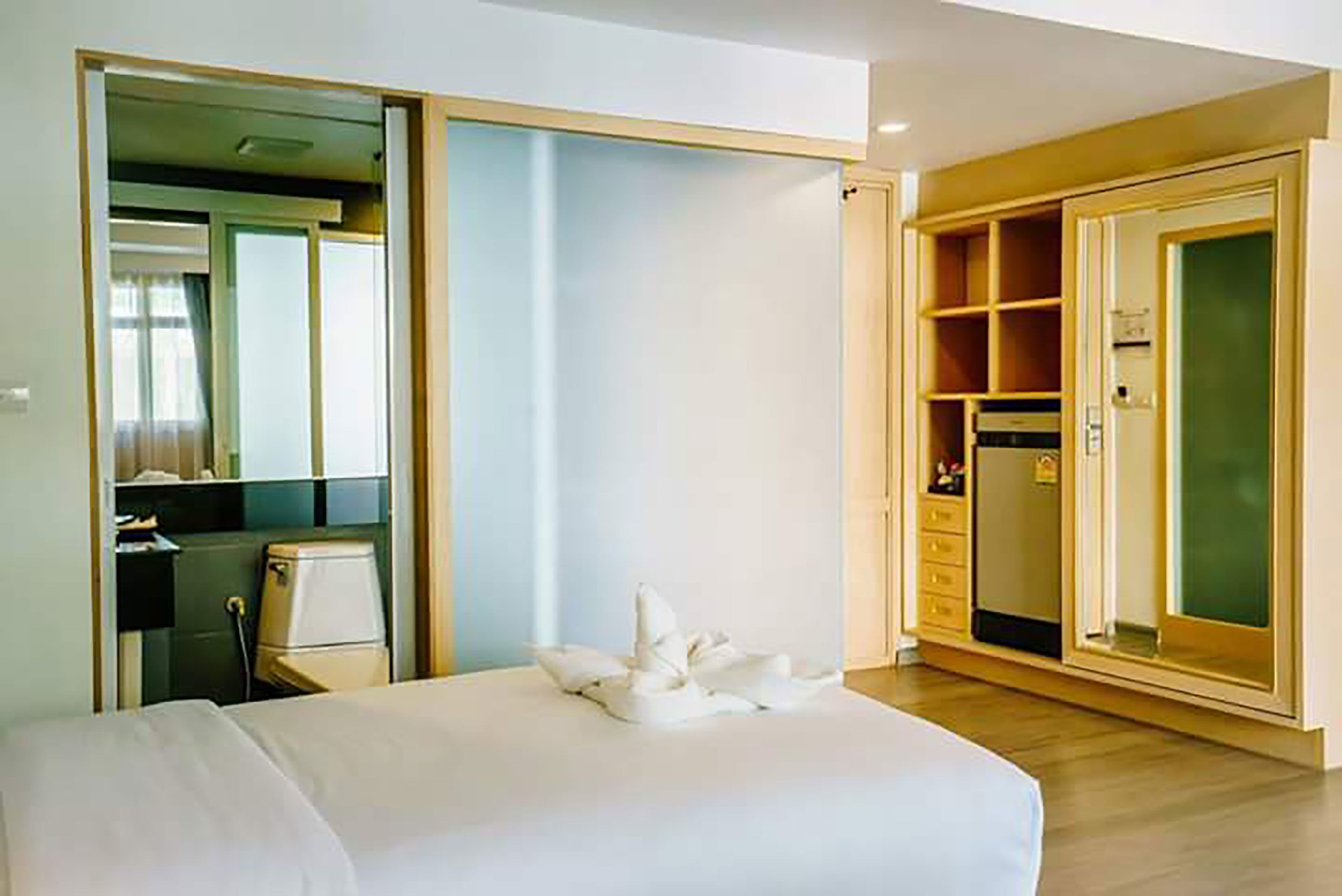 Quarto de hotel com cama, guarda-roupa, escrivaninha e espelho.