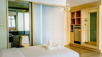 Quarto de hotel com cama, guarda-roupa, escrivaninha e espelho.
