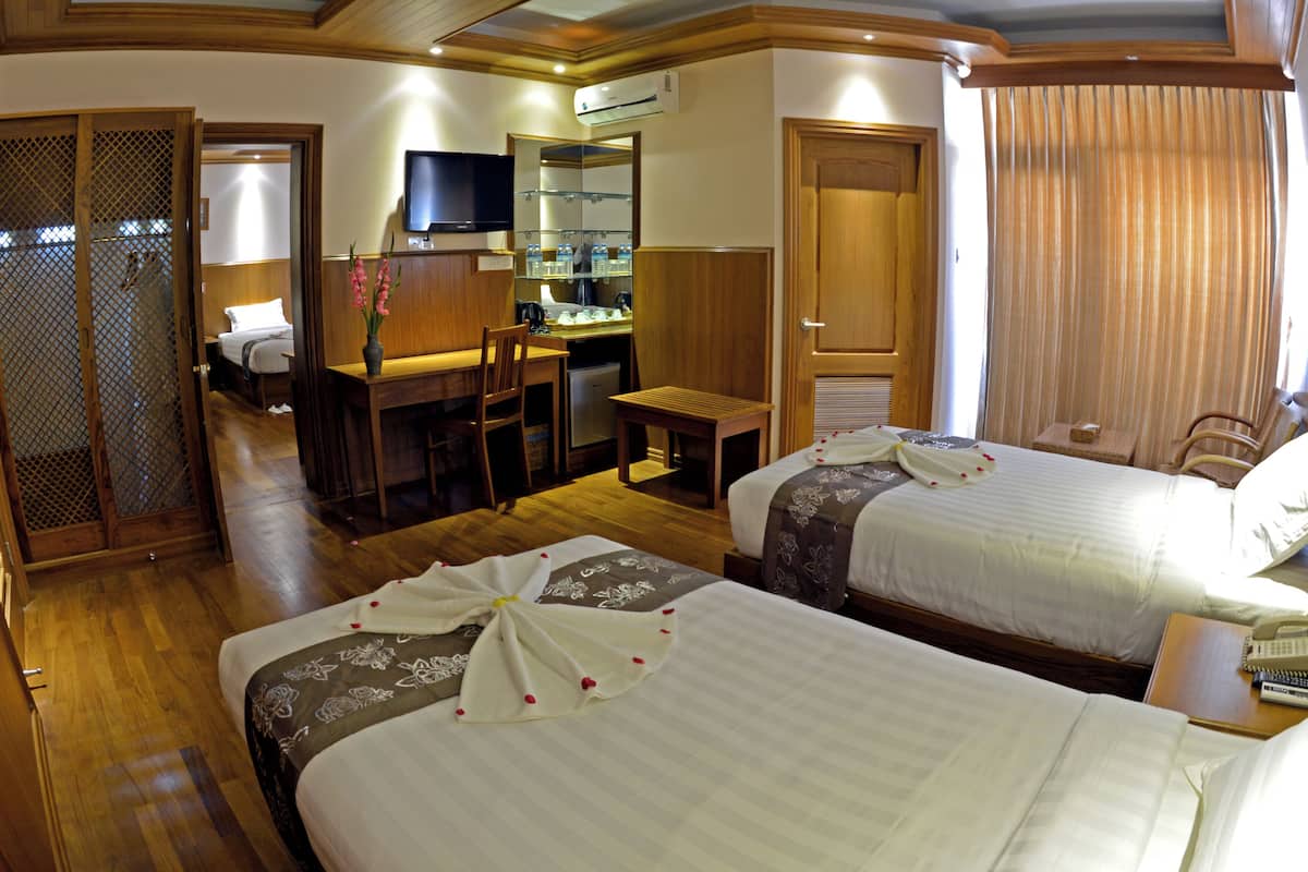 A hotel room with two beds, a desk, a chair, a TV, and a bathroom.