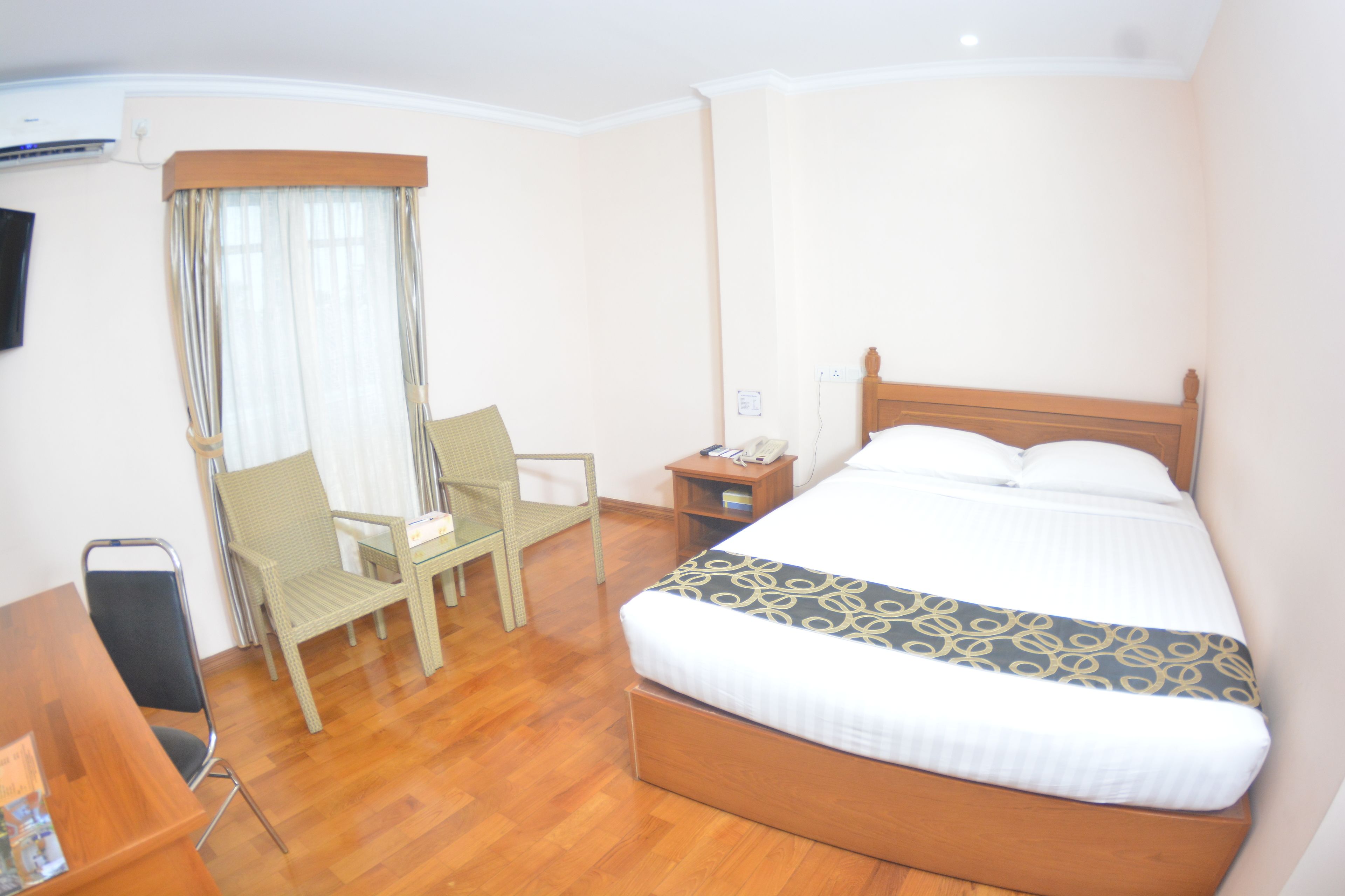 Une chambre d’hôtel avec un lit en bois, une chaise, un bureau et une table de chevet.